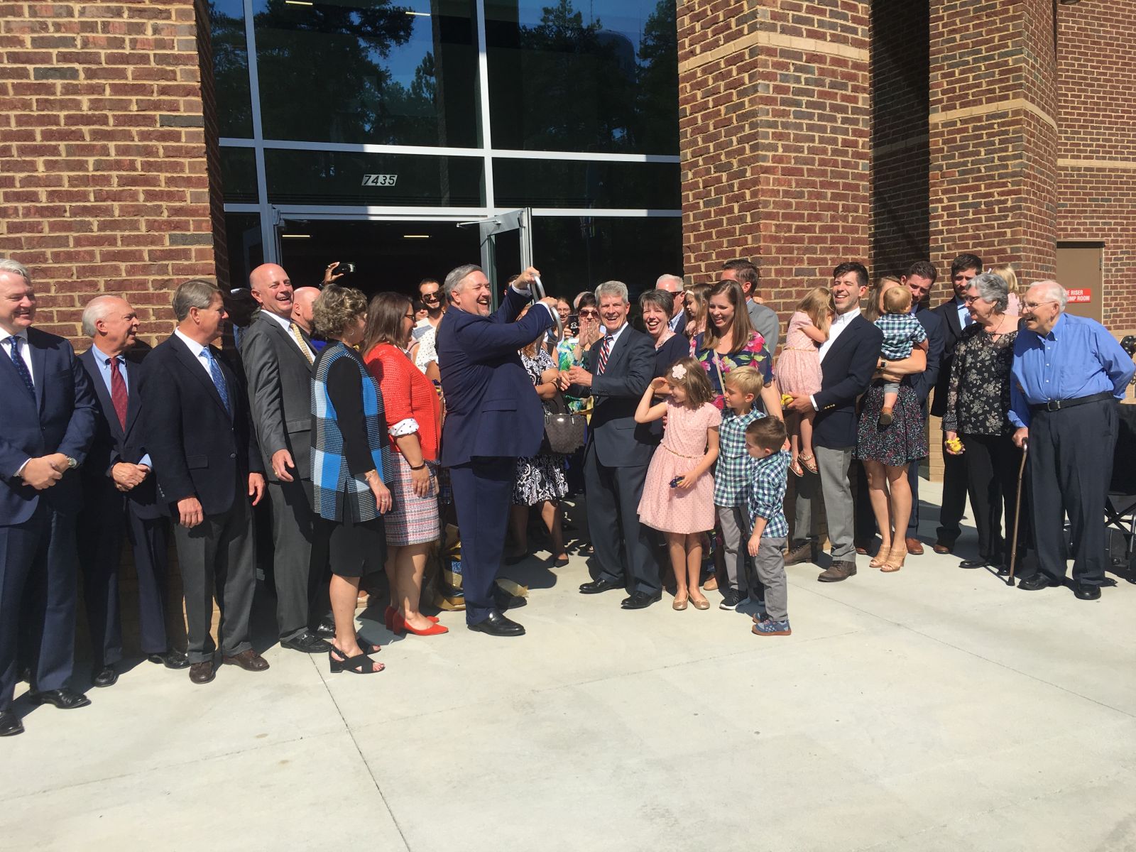 CIU president Mark Smith (holding scissors) and former president William Jones (facing Smith) celebrate after cutting the ribbon on the William H. Jones Global Business and IT Center. (Photo/Ren??e Sexton)