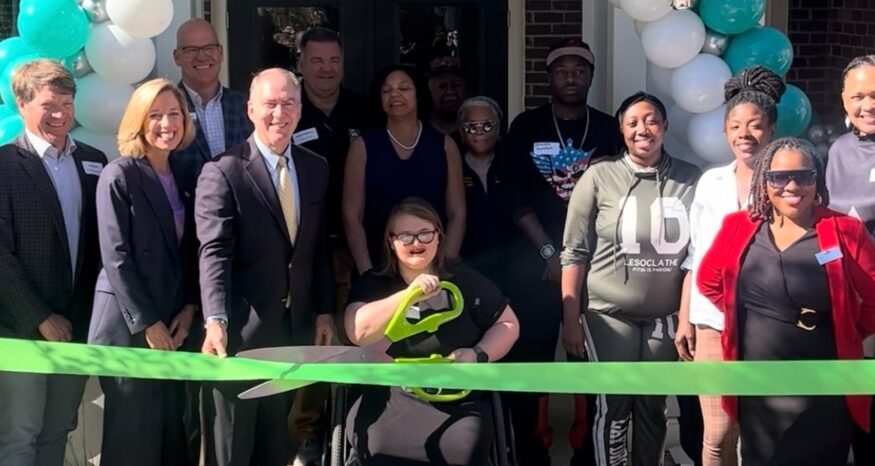 Katilyn Lengel puts the giant scissors to a ribbon during a dedication ceremony for Gateway at the Green. (Photo/Greenville Housing Fund)